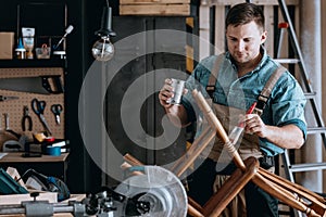 Smiling carpenter renovating wooden chair photo