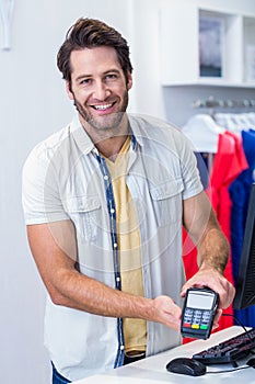 Smiling cashier showing credit card reader