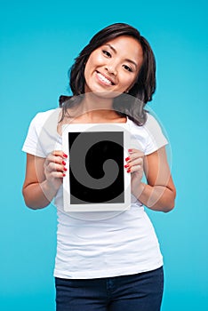Smiling casual asian woman showing blank tablet computer screen