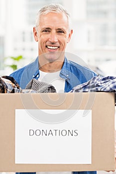 Smiling casual businessman holding donation box