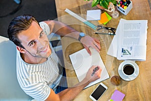 Smiling casual businessman writing in notepad