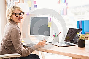 Smiling casual designer working at her desk