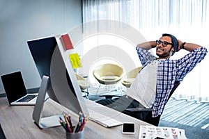 Smiling casual man with hands behind hand resting at desk