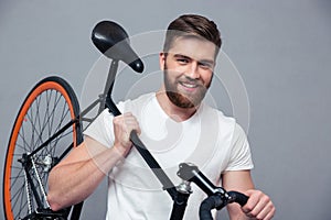 Smiling casual man holding bicycle on the shouder