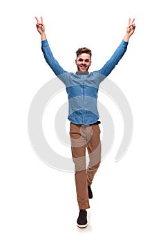 Smiling casual man stepping and making victory sign