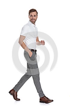 Smiling casual man walks and looks back over hisshoulder