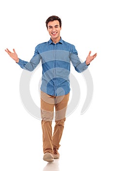 Smiling casual man welcoming you and walking forward