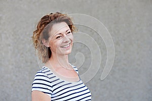 Smiling casual woman standing by wall