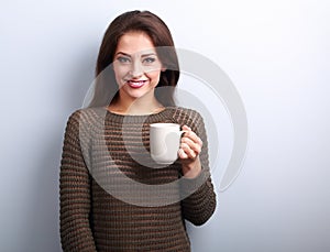 Smiling casual young woman with cup of tea looking happy