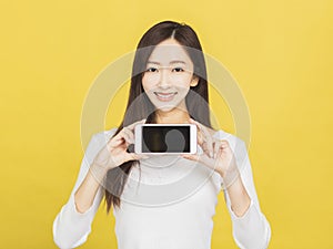 Smiling casual young woman holding smartphone and showing the blank screen