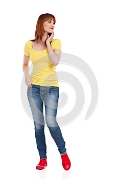 Smiling Casual Young Woman Standing With Hand On Chin And Looking Away