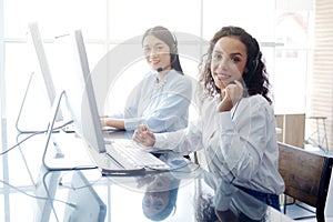 Smiling caucasian and asian women are call center or secretary operator is wearing a headset and a microphone for consultant to
