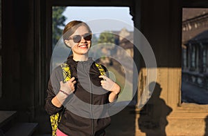 Smiling, caucasian backpacker tourist woman, with rucksack in Angkor Wat temple