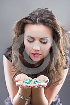 Smiling Caucasian Brunette Woman Holding New Year Confetti in Hands and Blowing Around photo
