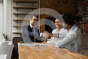 Smiling Caucasian realtor and African American family shaking hands