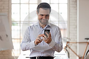 Smiling Caucasian businessman using modern cellphone in office