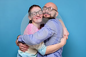 Smiling caucasian couple in glasses hugging on blue background