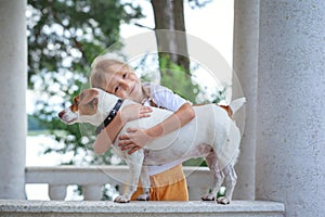 Smiling caucasian cute girl cuddling jack russell dog. A special bond between the kid and its dog