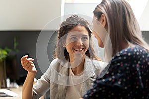 Smiling caucasian female manager communicating with asian colleague.