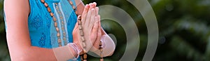 Smiling caucasian girl in namaste. girl hands close up with rosary in namaste gesture outdoor summer day. yoga, mindfulness,