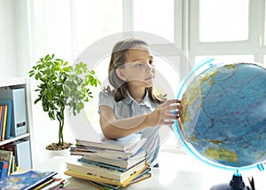 Smiling caucasian girl sitting at desk in class room and looking at workbook. Portrait of young schoolgirl studying at