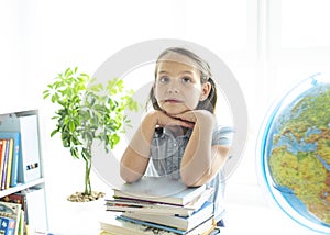 Smiling caucasian girl sitting at desk in class room and looking at workbook. Portrait of young schoolgirl studying at