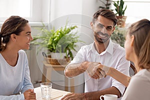 Smiling caucasian male manager, partner shaking hands thanking coworker photo