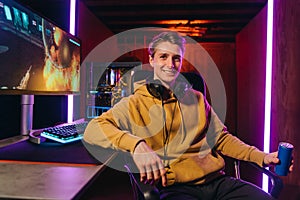Smiling caucasian pro gamer sitting by gaming setup at home