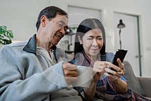 Smiling caucasian senior elderly couple grandparent using mobile together