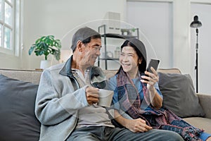 Smiling caucasian senior elderly couple grandparent using mobile together