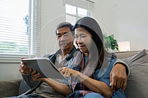 Smiling caucasian senior elderly couple grandparent using tablet together