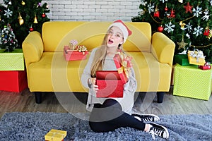 Smiling Caucasian Teenage lovely girl wearing red hat of Santa Claus and holding a big red gift box in Christmas and birthday