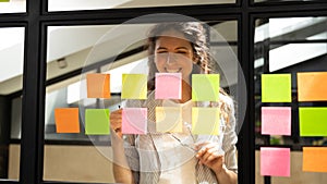 Smiling Caucasian woman employee develop idea on sticky notes