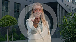Smiling Caucasian woman female business lady businesswoman HR manager outdoors near office building pointing finger at