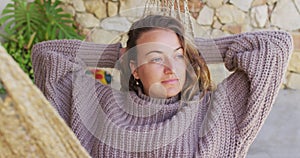 Smiling caucasian woman lying in hammock relaxing and enjoying the view from sunny garden patio