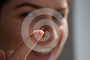 Smiling caucasian woman putting on a contact lens.