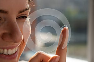 Smiling caucasian woman putting on a contact lens.
