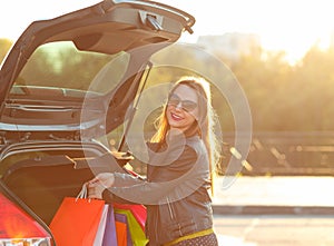 Smiling Caucasian woman putting her shopping bags into the car t