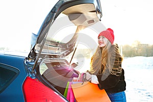 Smiling Caucasian woman putting her shopping bags into the car t