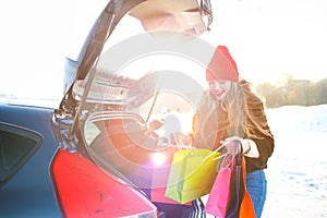 Smiling Caucasian woman putting her shopping bags into the car t