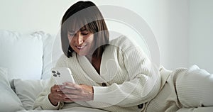 Smiling Caucasian Woman Texting on Phone While on Bed