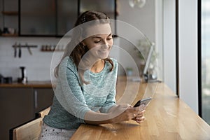 Smiling Caucasian woman use cellphone texting online