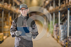 Smiling caucasian worker with clipboard in warehouse