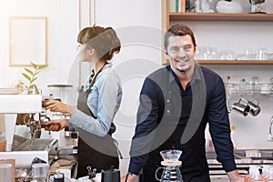 Smiling Caucasian Young barista couple love is wearing apron and working in the coffee shop. Start up for small cafe business