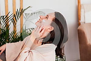 Smiling caucasian young woman applying cream on face at home. Morning beauty routine. Skincare concept