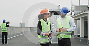 Smiling charismatic smart lady African engineer and good looking architect have a discussion about the construction site