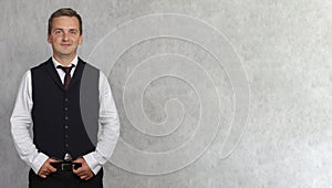 Smiling cheerful business man in a classic black vest posing on a light gray background in the studio.