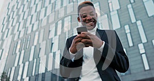 Smiling cheerful happy boy dressed in jacket stands in front of glass modern company building, break from work, man