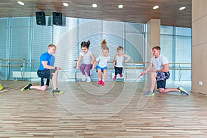 Smiling cheerful kids in school age playing together with jumping rope in gym. Children at physical education lesson in