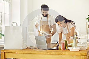 Smiling cheerful man and woman food delivery service workers packing online healthy meals orders